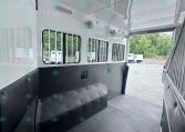 Interior of a horse trailer with padded walls, ventilated windows, and a rubber floor ready for loading horses