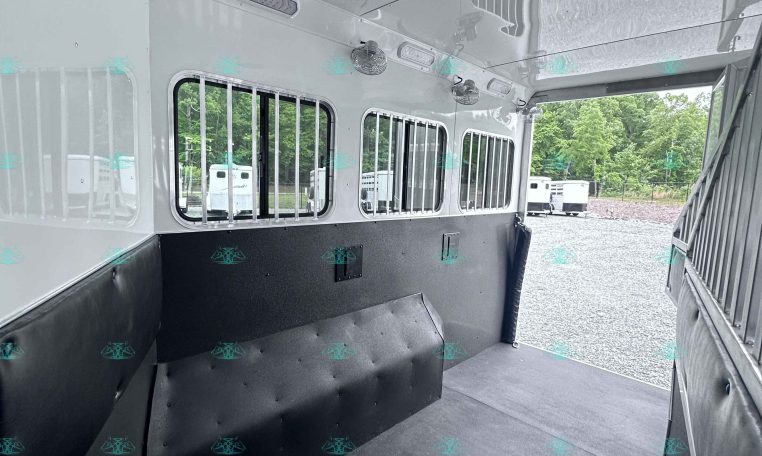 Interior of a horse trailer with padded walls, ventilated windows, and a rubber floor ready for loading horses