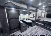 RV living area with dark wood cabinets, U-shaped dinette, and marble-patterned countertops; sunflowers on the table.