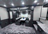 Dark wood RV dining area with a U-shaped bench and marble tabletop under overhead cabinets.
