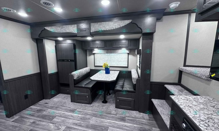 Dark wood RV dining area with a U-shaped bench and marble tabletop under overhead cabinets.