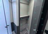Small RV bathroom with curved glass shower on the left and a dark wood vanity door on the right