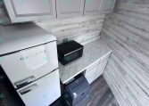 Small modern kitchen with white cabinets, marble countertops, and a silver Galanz refrigerator on the left.