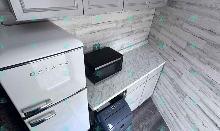 Small modern kitchen with white cabinets, marble countertops, and a silver Galanz refrigerator on the left.