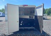 Open horse trailer with interior stall and partition, parked on gravel lot