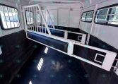 Interior of a white horse trailer with metal divider between stalls and blue padded walls