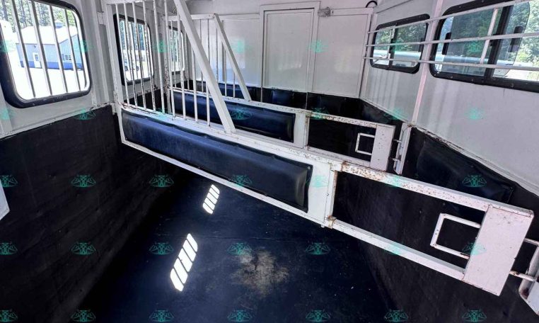 Interior of a white horse trailer with metal divider between stalls and blue padded walls
