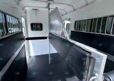 Interior of a horse trailer showing a divider in the center, with barred windows along the sides and diamond-plate flooring for traction.
