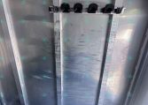 Inside of an aluminum trailer cargo area, showing a horizontal rack with five black U-shaped tie-down hooks mounted to a metal beam along the wall/ceiling.