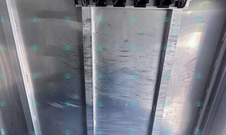 Inside of an aluminum trailer cargo area, showing a horizontal rack with five black U-shaped tie-down hooks mounted to a metal beam along the wall/ceiling.
