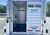 Rear view of an open aluminum livestock trailer with interior stalls and ramp, branded EXISS by Universal Trailer.