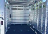 Interior of an empty aluminum livestock trailer with side slats and open rear ramp door