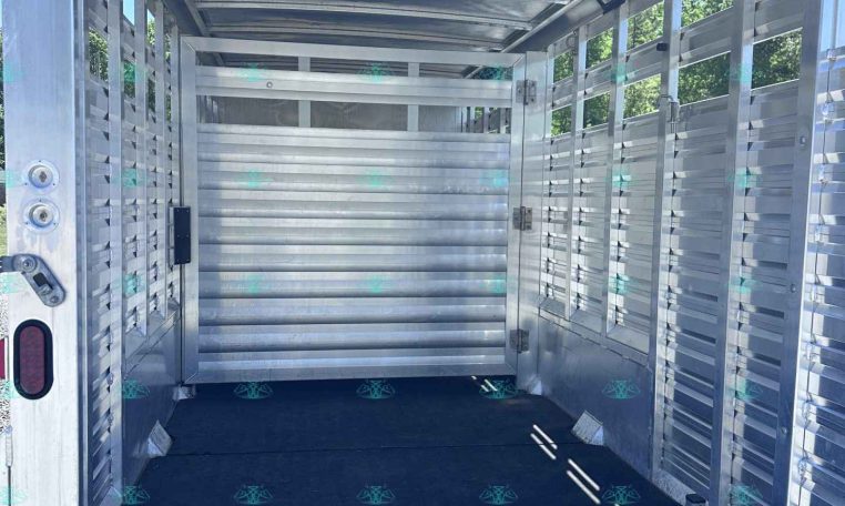Interior of an empty aluminum livestock trailer with side slats and open rear ramp door