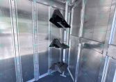 Interior of a silver aluminum trailer with vertical dividers and ceiling-mounted rails; black plastic supports or guards hang from a central post inside the trailer.