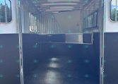 Open horse trailer with metal stalls along the sides, empty interior, and blue lower panels.