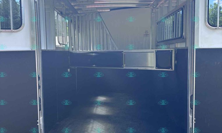 Open horse trailer with metal stalls along the sides, empty interior, and blue lower panels.