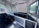 Interior of a aluminum horse trailer with divided stalls and padded side panels, view toward the back of the trailer