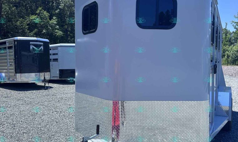 White travel trailer with rounded edges and diamond-plate front, parked on a gravel lot; Valley Trailers logo visible on the side.