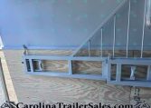 Metal trailer frame with a diagonal support arm mounted against a plywood wall, watermark 'CarolinaTrailerSales.com' along the bottom.