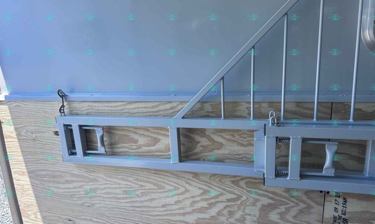 Metal trailer frame with a diagonal support arm mounted against a plywood wall, watermark 'CarolinaTrailerSales.com' along the bottom.