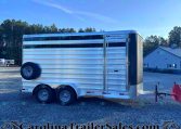 Polished aluminum livestock trailer with three axles and a side access door on a gravel lot, watermarked CarolinaTrailerSales.com
