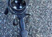 Close-up of a trailer hitch coupler and wiring harness on a metal frame, set on gravel ground.