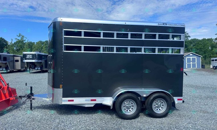 Black stock trailer with horizontal screened vents, tandem wheels, parked on gravel lot; watermark CarolinaTrailersales.com visible in foreground.