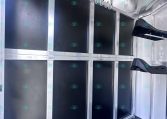 Inside a silver horse trailer with black divider panels and a row of metal hooks along the top for tack storage.