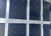 Interior of a trailer with blue wall panels, silver framing, and a row of metal hooks along the ceiling for securing gear.