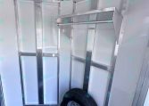 Interior of a metal utility trailer showing aluminum framing and a mounted spare tire on the floor