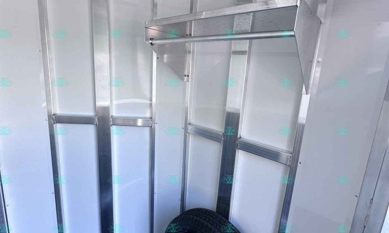 Interior of a metal utility trailer showing aluminum framing and a mounted spare tire on the floor