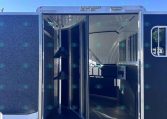 Open horse trailer with interior stalls and partition rails, blue exterior, parked on gravel.