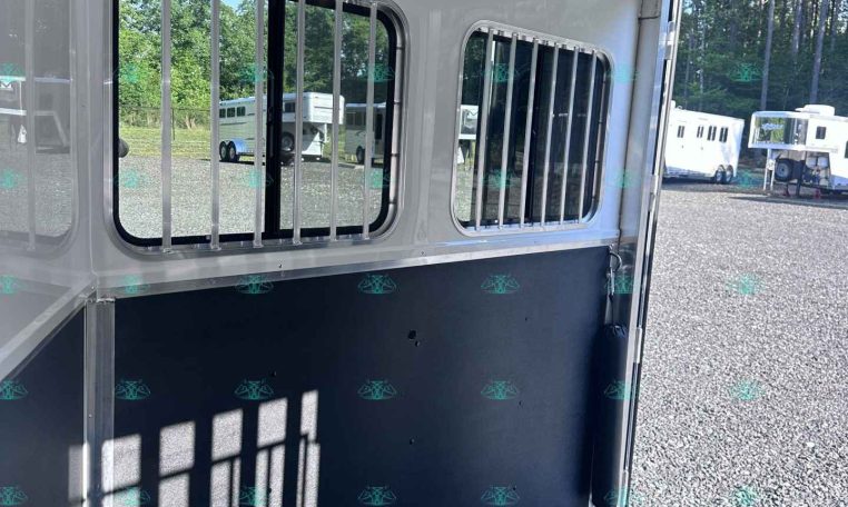 Interior of a white horse trailer with barred windows, a blue lower wall divider, and overhead LED lights inside the stall area