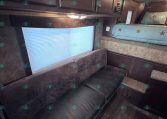 Cozy camper interior with dark wood cabinets, a gray sofa, and a blue star-patterned bunk bed against the wall.