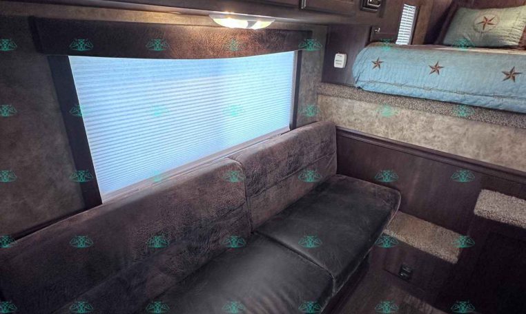 Cozy camper interior with dark wood cabinets, a gray sofa, and a blue star-patterned bunk bed against the wall.