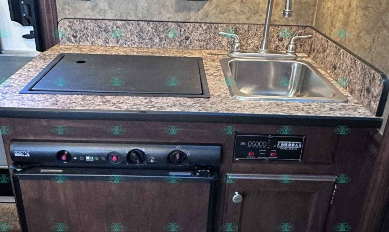 RV kitchen kitchenette with granite countertop, built-in stove, and stainless steel sink.