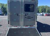 Rear view of a silver trailer with dual rear doors and lowered loading ramp on a gravel lot; 'SMC Trailers' logo visible on doors.