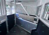 Interior of a stainless horse trailer with metal dividing partitions and a slanted floor ramp for loading horses or livestock.