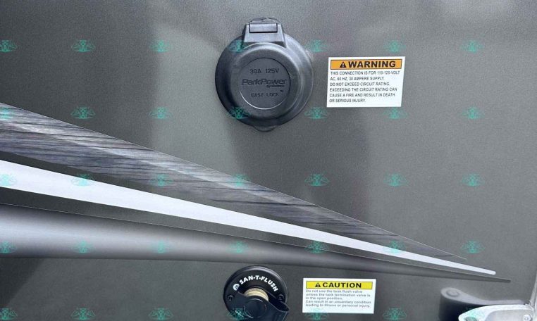 Back of a utility trailer showing a fuel/ electrical hookup caps and a city water connection panel with caution labels (carolinaTrailerSales.com text visible).