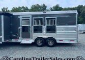 Side view of a dark gray Merhow horse trailer with three barred windows and tandem wheels parked on gravel.