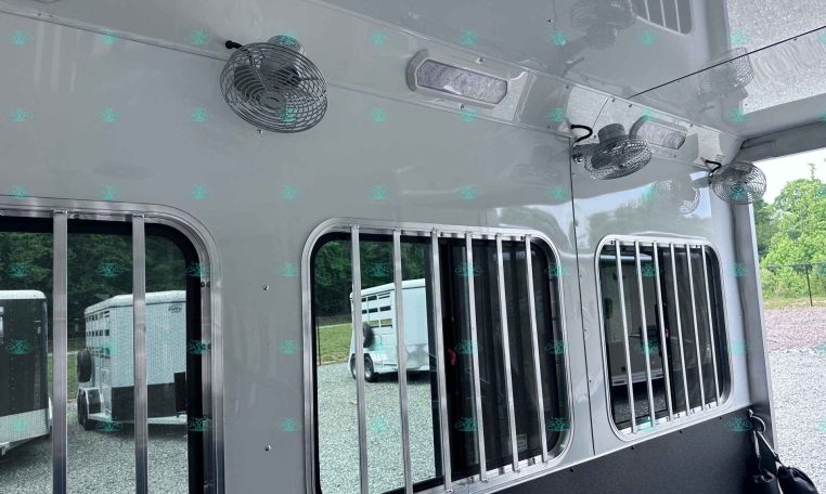 Side view of a gray horse trailer with barred windows and mounted fans on the exterior ceiling area