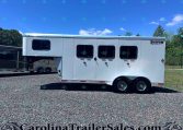 White Shadow Select horse trailer with three side windows, parked on a gravel lot under a clear blue sky.