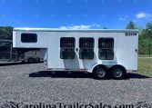 White Shadow Select horse trailer with three barred side windows, parked on a gravel lot under a bright blue sky.