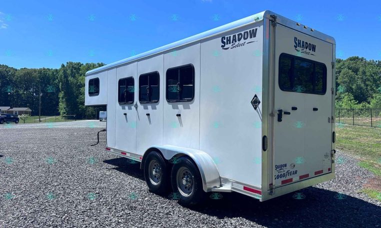 White Shadow Select horse trailer parked on a gravel lot under a clear blue sky.