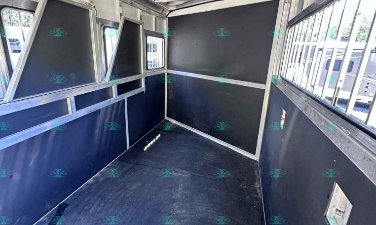 Interior of a metal trailer with black partition panels and aluminum framing, viewed from the doorway to the back end, near the windows on the right side