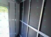Interior of a metal trailer showing black wall panels and silver framing with ceiling hooks along the top edge.