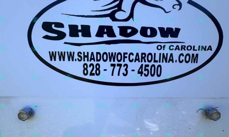 Oval Shadow of Carolina logo with a stylized horse head, website www.shadowofcarolina.com and phone 828-773-4500 on a blue trailer surface.